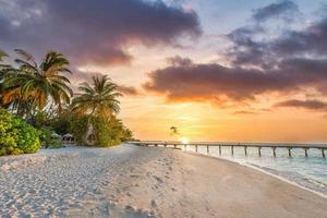 fantastische nahaufnahmeansicht des sonnenuntergangstrandes. tropische inselstrandlandschaft exotische palmenküste, holzsteg. sommer romantischer urlaub, urlaub erstaunliche natur landschaftlich. Relaxparadies, schöner Sonnenaufgangshimmel foto