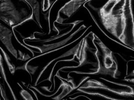 schwarzer satinierter texturhintergrund mit flüssigen wellen oder wellenfalten. Tapetendesign foto