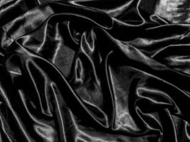 schwarzer satinierter texturhintergrund mit flüssigen wellen oder wellenfalten. Tapetendesign foto