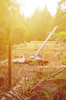 der Prozess des Baus eines Holzhauses aus Holzbalken mit zylindrischer Form. Kran in funktionstüchtigem Zustand foto