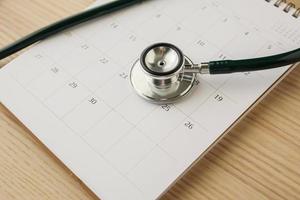 stethoskop mit kalenderseite datum auf holztisch hintergrund arzttermin medizinisches konzept foto