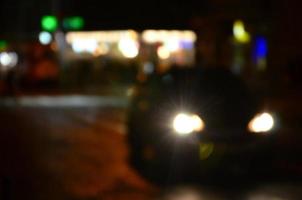 verschwommene Nachtszene des Verkehrs auf der Fahrbahn. defokussiertes Bild von Autos, die mit leuchtenden Scheinwerfern fahren. Bokeh-Kunst foto