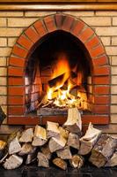 Holzstapel und Feuer im gemauerten Innenkamin foto