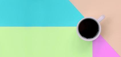 kleine weiße kaffeetasse auf texturhintergrund aus modepapier in pastellrosa, blau, korallen- und limettenfarben foto