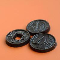 drei schokoladenprodukte in form von euro-, usa- und japan-münzen liegen auf einem orangefarbenen kunststoffhintergrund. ein Modell von Geldmünzen in essbarer Form foto
