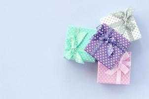 Haufen von kleinen farbigen Geschenkboxen mit Bändern liegt auf violettem Hintergrund foto