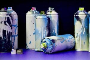 Stillleben mit einer großen Anzahl gebrauchter bunter Spraydosen mit Aerosolfarbe, die auf der behandelten Holzoberfläche in der Graffiti-Werkstatt des Künstlers liegen. schmutzige und befleckte Dosen für Sprühkunst foto