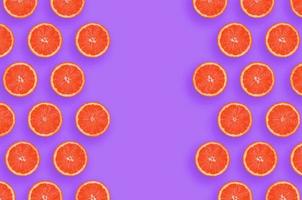 Rahmen aus Grapefruit-Zitrusscheiben auf hellviolettem Hintergrund foto