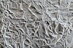 Dünnes zerknittertes Blatt aus zerkleinertem Zinn-Aluminium-Silberfolie-Hintergrund mit glänzend zerknitterter Oberfläche für Textur foto