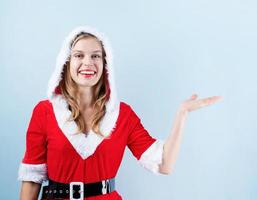 nahaufnahme der kaukasischen glücklichen frau, die weihnachtsmannkleidung trägt, lacht und zeigt foto