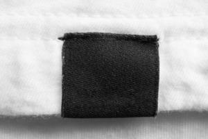 schwarzes leeres Wäschepflegeetikett auf weißem Baumwollhemdhintergrund foto