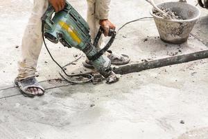 bauarbeiter, der bohrhammer verwendet, der betonoberfläche bohrt foto