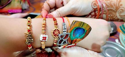 Hand einer Dame, die während des hinduistischen Rakshabandhan-Rituals Rakhi in die Hand eines Mannes bindet foto