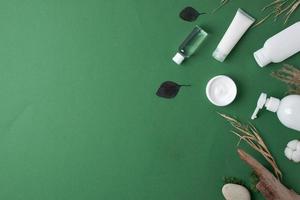 kosmetische hautpflegeprodukte mit blumen und holz auf grünem hintergrund. flach liegend, kopierraum foto