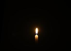 Kerze brennt vor schwarzem Hintergrund foto