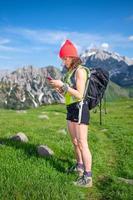 frau im urlaub in den bergen auf einem ausflug checkt die emails vom smarphone foto