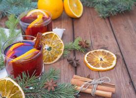 weihnachtsglühwein auf einem hölzernen hintergrund mit gewürzen und fichtenzweigen und getrockneter orange. foto