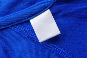 leeres weißes Wäschepflegeetikett auf blauem Stofftexturhintergrund foto