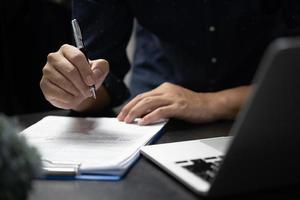 Hand mit Stift schreiben Papierkram Geschäftsdokument Finanzinvestition oder Unterschrift Vertrag Job und Versicherung auf dem Schreibtisch. foto