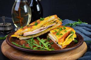 Gerösteter Toast in Rührei mit Schinken, Kräutern und Cheddar-Käse. leckeres gegrilltes Frühstückssandwich foto