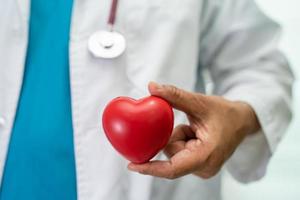 Arzt, der ein rotes Herz in der Krankenstation hält, gesundes, starkes medizinisches Konzept. foto