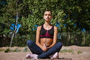 junge frau in sportkleidung sitzt am strand, um musikhören zu lernen foto