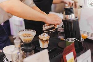 Barista-Hand, die Kakaopulver auf Eisschokolade streut. foto