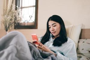 junge erwachsene alleinstehende frau, die morgens ein smartphone verwendet, um mit einem freund über eine soziale nachrichten-app zu chatten foto