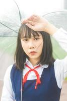 porträt der jungen frau mit kurzen haaren tragen japanische studentenuniform mit regenschirm foto