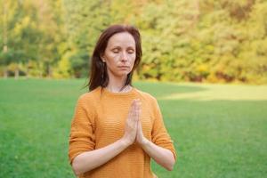 Reife, fitte, gesunde Frau mittleren Alters, die draußen in natürlicher Ruhe Yoga praktiziert foto