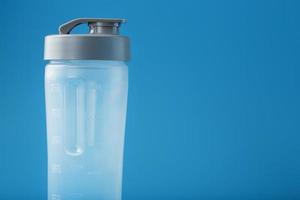 Shaker ist ein leerer Smoothie-Plastikbecher auf blauem Hintergrund. foto