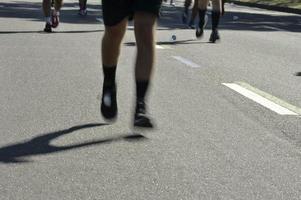 Straßenrennen, das die verschwommenen Bewegungsbeine der Läufer zeigt foto