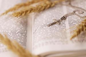 Silberhalskette mit Kruzifixkreuz auf christlichem Bibelbuch auf schwarzem Holztisch. Gott mit der Kraft der Heiligkeit um Segen bitten foto