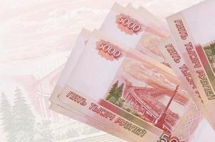 5000 russische Rubel-Scheine liegen im Stapel auf dem Hintergrund einer großen halbtransparenten Banknote. abstrakte Darstellung der Landeswährung foto