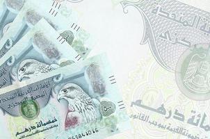 500 VAE-Dirham-Scheine liegen im Stapel auf dem Hintergrund einer großen halbtransparenten Banknote. abstrakter betriebswirtschaftlicher hintergrund foto