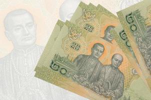 20 thailändische Baht-Scheine liegen im Stapel auf dem Hintergrund einer großen halbtransparenten Banknote. abstrakte Darstellung der Landeswährung foto