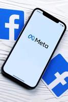 charkow, ukraine - 29. oktober 2021 iphone 12 pro mit meta- oder metaverse-logo liegt auf holztisch mit zwei facebook-logos aus papier. foto