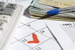 1041 Einkommensteuererklärung für Nachlässe und Trusts leer mit Dollarnoten, Taschenrechner und Stift auf Kalenderseite mit markiertem 15. April foto