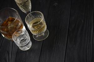 Verschiedene alkoholische Getränke im Glas auf Holzoberfläche auf dunklem Hintergrund. Luxus-Elite-Alkohol in Glasbechern. zurückhaltende Szene foto