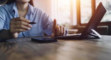 Geschäftsfrau arbeitet mit Laptop-Computer, Tablet und Smartphone im modernen Büro mit virtuellem Symboldiagramm im Modernoffice im Morgenlicht foto