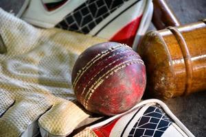 training von cricket-sportgeräten auf dem boden, lederball, handschuhe und schläger, weicher und selektiver fokus auf den ball. foto