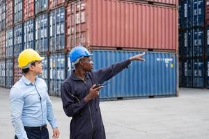 selektiver Fokus auf afrikanische schwarze Arbeiter, während sie mit dem Vorgesetzten sprechen und diskutieren und den Zustand aller Containertransporte, Personen und Arbeiter bei der Frachtlieferung, dem Import und Export inspizieren. foto