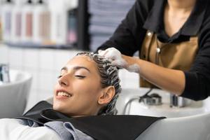 schöne kaukasische frauen fühlen sich entspannt und wohl, während sie sich mit shampoo und massage die haare waschen. friseurstudio mit stilvollem haar, schönheits- und modekonzept. foto