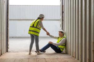 junge erwachsene männer und frauen industriearbeiter halten hand, ermutigen und jubeln nach einem harten arbeitstag am import- oder exportstandort für containertransporte. arbeitsplatzkonzept für teamarbeit und freundschaft. foto