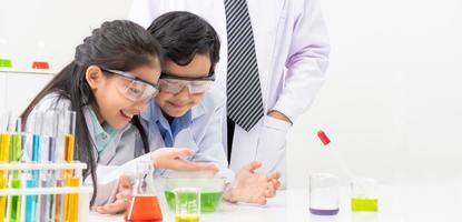 junge asiatische junge und mädchen, die schützendes google tragen, während sie lernen und wissenschaftliche experimente im klassenzimmer mit dem lehrer machen. Lernen und Spaß haben. konzept des klassenzimmers für chemiker oder biologie. foto