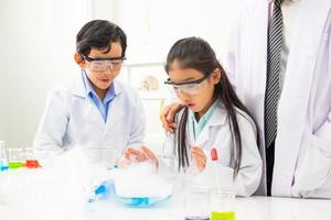 junge asiatische junge und mädchen, die schützendes google tragen, während sie lernen und wissenschaftliche experimente im klassenzimmer mit dem lehrer machen. Lernen und Spaß haben. konzept des klassenzimmers für chemiker oder biologie. foto