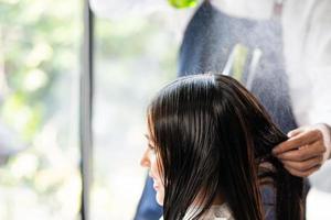 nahaufnahme schuss an der hand des haares stilvoll, während sprühwasser vor dem haarschnitt und friseur und behandlung beim stylen der haare für den kunden. Beruf, Schönheits- und Modedienstleistungsberuf. foto