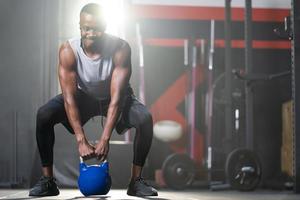 Starke erwachsene schwarze afrikanische Männer schwingen Kettlebell, um Crossfit-Übungen und Gewichtheben im Fitnessstudio zu machen, um Körperkraft und feste Armmuskeln und eine gute körperliche Gesundheit zu trainieren. foto