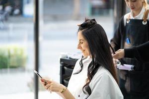 kaukasische frauen lächeln und sind glücklich mit stilvollem haar, während sie die haare schneiden und eine chirurgische gesichtsmaske tragen, während sie die haare für den kunden stylen. Berufliche Tätigkeit, Schönheits- und Modeservice neue Normalität foto