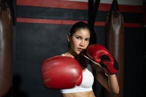 erwachsene asiatische frauen, die einen elastischen verband verwenden, um ihre hände zu binden, bevor sie einen boxhandschuh für den boxer-trainingskurs, sport-, fitness- und übungskonzept für gute gesundheit und starke muskeln und körper anziehen. foto